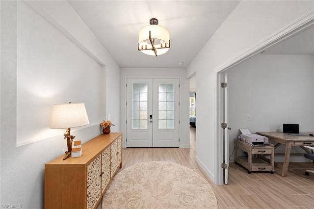 44810 Marina Ln, Punta Gorda, FL 33982 Entryway featuring double French doors, wood-finish flooring, a built-in recessed wall detail, and an overhead drum pendant light