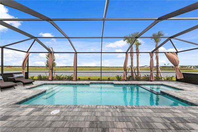44810 Marina Ln, Punta Gorda, FL 33982 Screened-in outdoor pool and spa with integrated steps, surrounded by patterned paver flooring and mature palm trees
