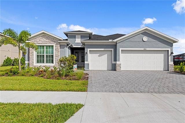 44810 Marina Ln, Punta Gorda, FL 33982 Stucco exterior with stone accents, mature landscaping, two-car garage, and a paver driveway