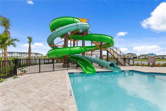 44810 Marina Ln, Punta Gorda, FL 33982 Resort-style pool area featuring a large water slide structure, a paved pool deck, and perimeter fencing