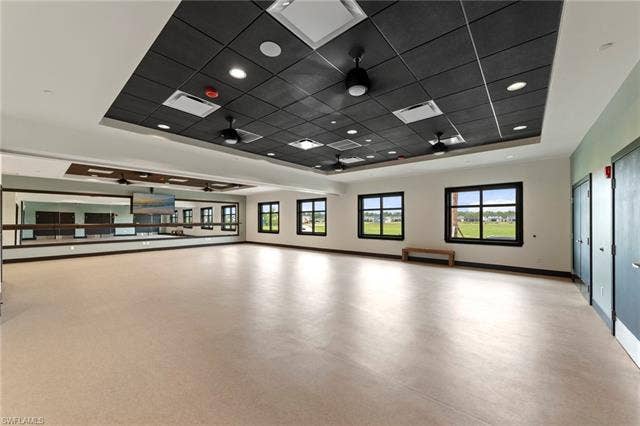 44810 Marina Ln, Punta Gorda, FL 33982 Spacious room featuring a full wall of mirrors with ballet barres, multiple windows, and a dropped ceiling with integrated lighting and ceiling fans