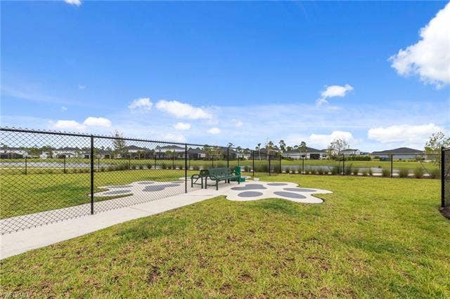 44810 Marina Ln, Punta Gorda, FL 33982 Fenced green space featuring a concrete pathway, a decorative paw print-shaped concrete pad, and a bench
