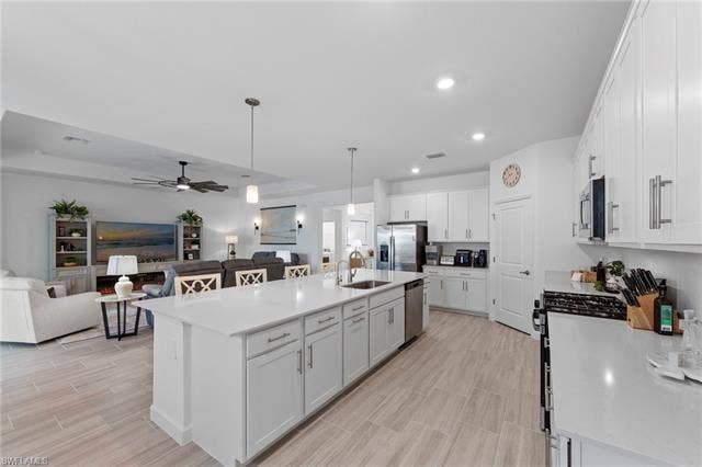 44810 Marina Ln, Punta Gorda, FL 33982 Open-concept living space featuring a kitchen island with sink, white shaker cabinetry, stainless steel appliances, and wood-finish tile flooring