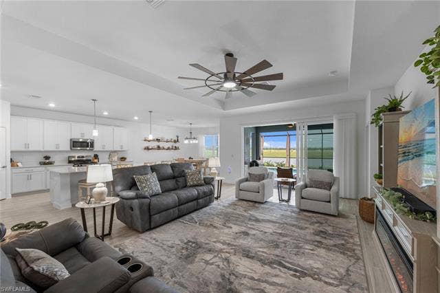 44810 Marina Ln, Punta Gorda, FL 33982 Open-concept living space featuring a tray ceiling, ceiling fan, and sliding glass doors
