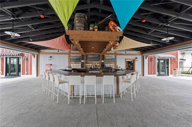 44810 Marina Ln, Punta Gorda, FL 33982 Expansive bar area featuring a U-shaped countertop, exposed beam ceiling, and a large roll-up door
