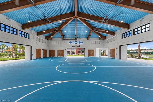 44810 Marina Ln, Punta Gorda, FL 33982 Indoor basketball court featuring a blue playing surface with white line markings, a high vaulted ceiling with exposed wood beams, and large open doorways