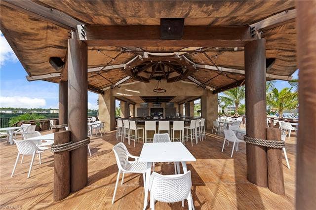 44810 Marina Ln, Punta Gorda, FL 33982 Covered outdoor dining area featuring a full-service bar with seating, wood-finish flooring, and structural columns with rope detailing