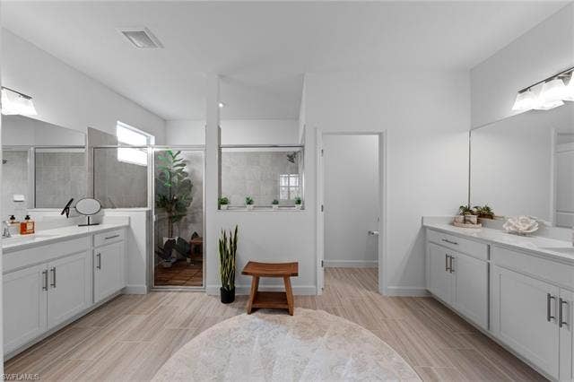44810 Marina Ln, Punta Gorda, FL 33982 Spacious bathroom with dual vanities, wood-finish flooring, and a glass-enclosed shower
