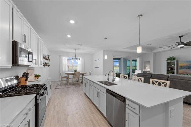 44810 Marina Ln, Punta Gorda, FL 33982 Kitchen featuring white cabinetry, stainless steel appliances, a center island with a sink, pendant lighting, and wood-finish flooring