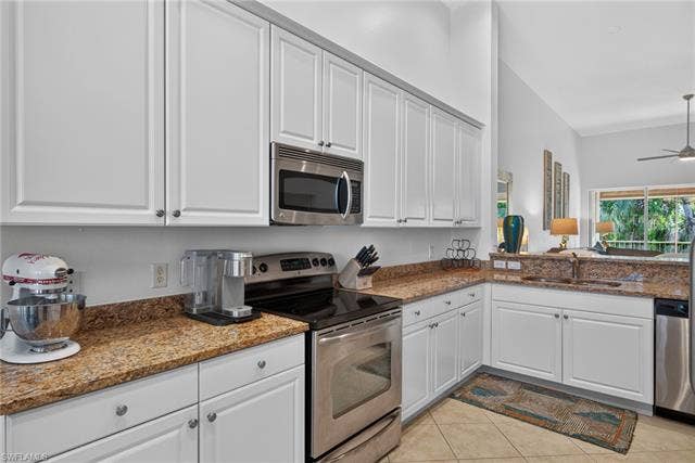14543 Abaco Lakes Dr, #202, Fort Myers, FL 33908 Gleaming chef's kitchen equipped with sleek stainless steel appliances, abundant cabinetry, matching granite workspace, and an integrated dual sink.