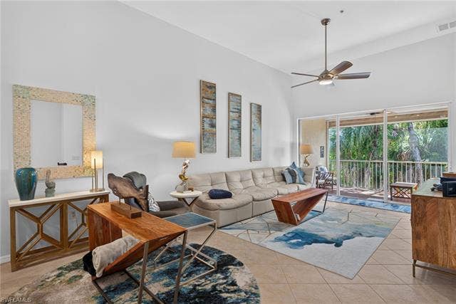 14543 Abaco Lakes Dr, #202, Fort Myers, FL 33908 Spacious living room with high vaulted ceilings, durable tile flooring, and massive sliding glass doors opening to a private screened lanai