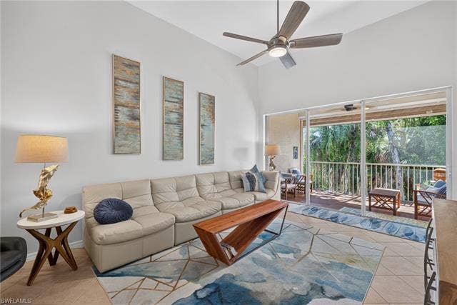 14543 Abaco Lakes Dr, #202, Fort Myers, FL 33908 Inviting living space anchored by high ceilings and sliding glass doors that seamlessly connect indoor relaxation with a lush, peaceful outdoor view.