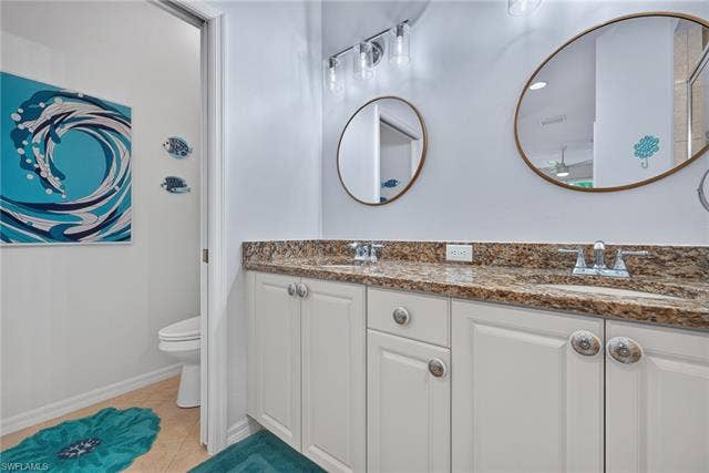 14543 Abaco Lakes Dr, #202, Fort Myers, FL 33908 Primary bathroom vanity view highlighting the gorgeous granite countertops, dual sinks, stylish coastal accents, and a separate private water closet.