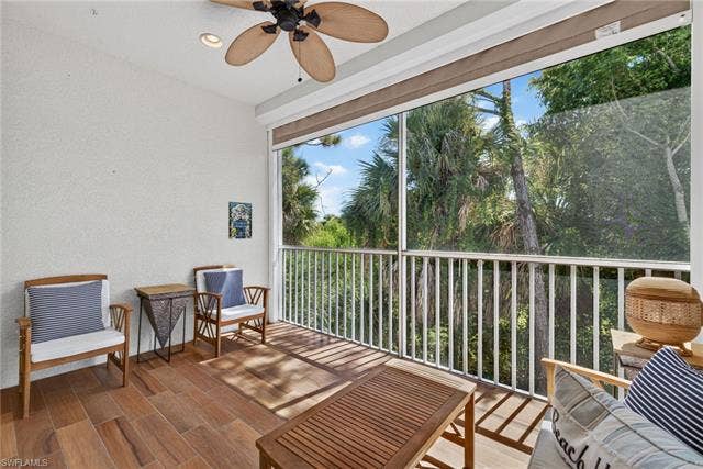 14543 Abaco Lakes Dr, #202, Fort Myers, FL 33908 Private screened lanai featuring durable tile flooring, a tropical leaf ceiling fan, and peaceful, lush nature views perfect for outdoor relaxation.
