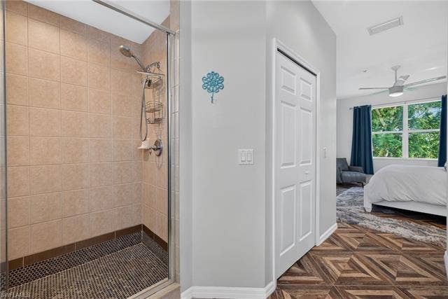 14543 Abaco Lakes Dr, #202, Fort Myers, FL 33908 Spacious primary walk-in shower featuring a glass enclosure, tiled walls, and a textured pebble floor, seamlessly transitioning out to the bedroom area.