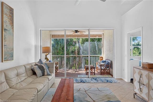 14543 Abaco Lakes Dr, #202, Fort Myers, FL 33908 Light-filled living room featuring large triple sliding glass doors that open completely to a peaceful, screened-in lanai surrounded by nature.