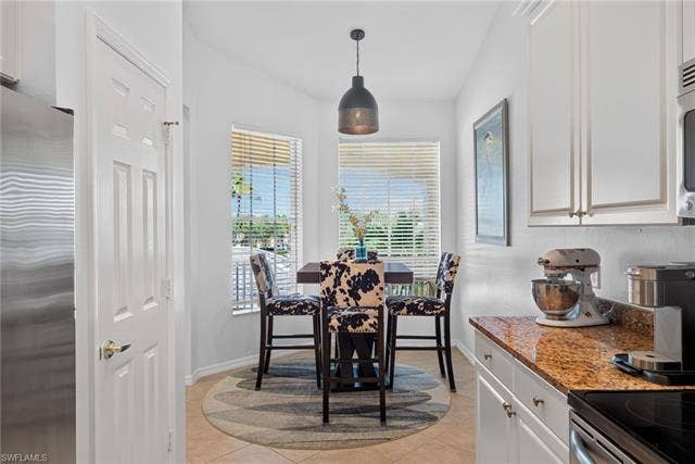 14543 Abaco Lakes Dr, #202, Fort Myers, FL 33908 Sun-filled primary dining area located right off the kitchen, featuring a modern pendant light and large windows that draw in plenty of natural light.