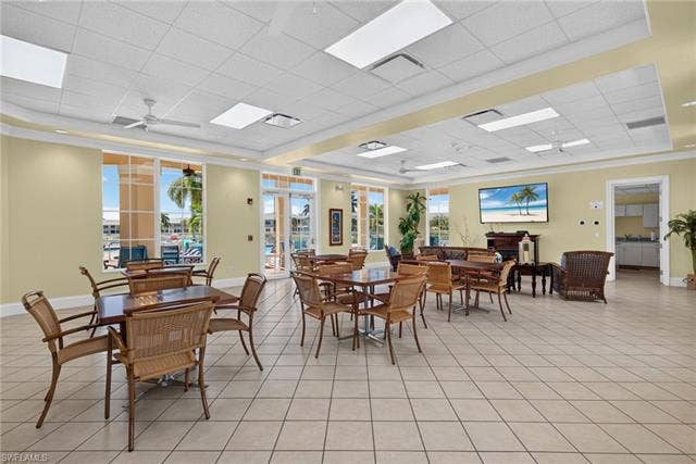 14543 Abaco Lakes Dr, #202, Fort Myers, FL 33908 Spacious community clubhouse social room featuring versatile card tables, comfortable seating areas, a flat-screen TV, and pool-view access.