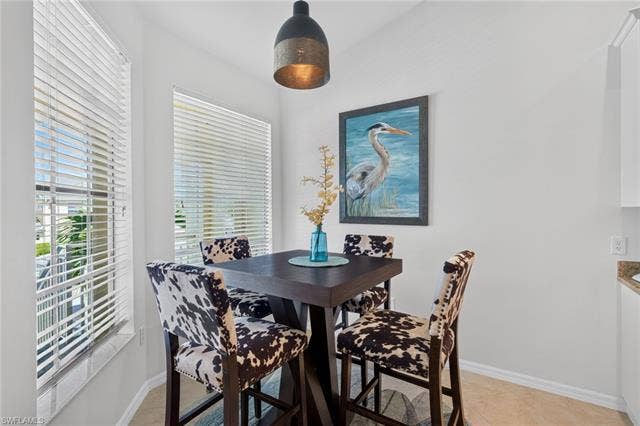 14543 Abaco Lakes Dr, #202, Fort Myers, FL 33908 Charming primary dining space detailed with a modern industrial pendant light, coastal artwork, and bright windows that overlook the community.