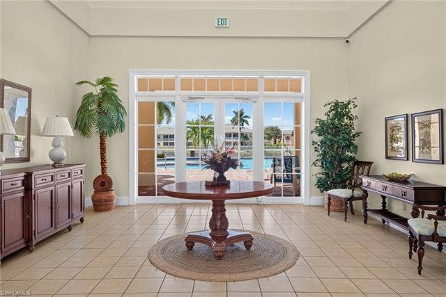 14543 Abaco Lakes Dr, #202, Fort Myers, FL 33908 Elegant community clubhouse lobby featuring high ceilings, a grand center table, and large French doors opening directly to the resort-style pool area.