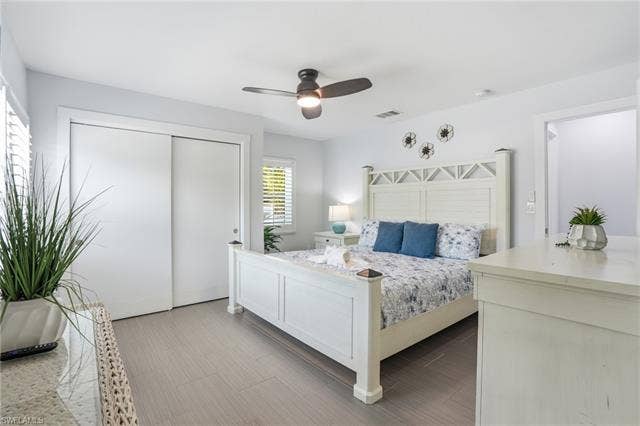 240 Fairweather Ln, Fort Myers Beach, FL 33931 Bedroom featuring wood-finish flooring and white plantation shutters - Virtually Edited Image