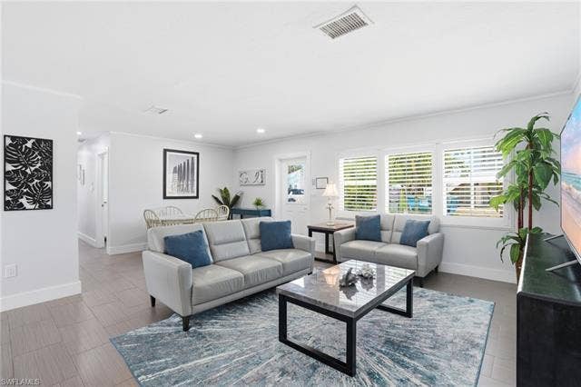 240 Fairweather Ln, Fort Myers Beach, FL 33931 Bright living area featuring wood-finish flooring, white plantation shutters, and recessed lighting - Virtually Edited Image