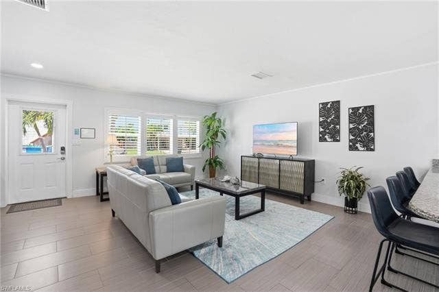 240 Fairweather Ln, Fort Myers Beach, FL 33931 Bright living area featuring light-toned tile flooring, white walls, and recessed lighting - Virtually Edited Image