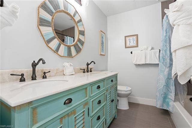 240 Fairweather Ln, Fort Myers Beach, FL 33931 Double vanity with white countertop and distressed turquoise cabinetry - Virtually Edited Image