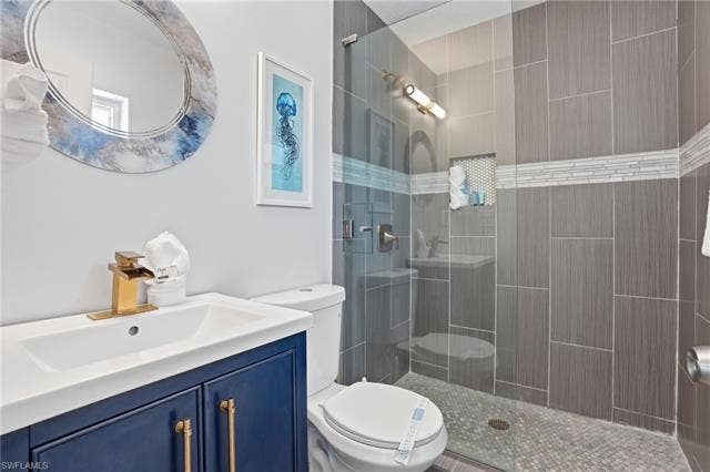 240 Fairweather Ln, Fort Myers Beach, FL 33931 Bathroom featuring a glass-enclosed shower with vertical gray tile, a mosaic tile accent band, and a built-in niche - Virtually Edited Image
