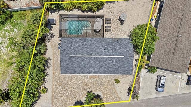 240 Fairweather Ln, Fort Myers Beach, FL 33931 Property featuring a screened-in swimming pool, a spacious paver patio, and mature perimeter landscaping - Virtually Edited Image