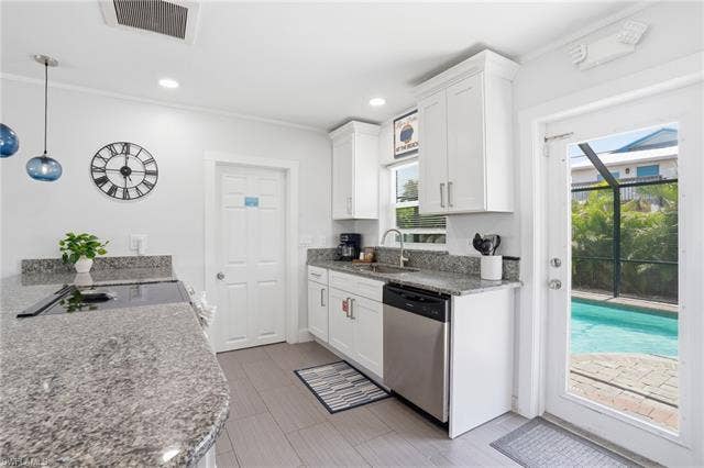 240 Fairweather Ln, Fort Myers Beach, FL 33931 Kitchen featuring white shaker cabinetry, stainless steel appliances, speckled stone countertops, and gray wood-finish flooring - Virtually Edited Image