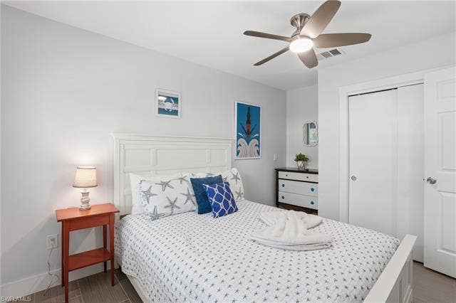 240 Fairweather Ln, Fort Myers Beach, FL 33931 Bedroom featuring a white paneled headboard and wood-finish flooring - Virtually Edited Image