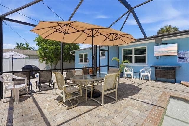 240 Fairweather Ln, Fort Myers Beach, FL 33931 Screened patio featuring paver flooring, a light blue exterior, and a pool border - Virtually Edited Image