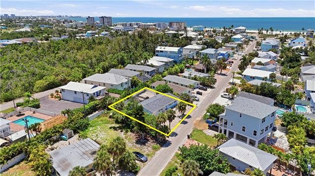 240 Fairweather Ln, Fort Myers Beach, FL 33931 Coastal community setting featuring a single-story residence with mature palm trees - Virtually Edited Image