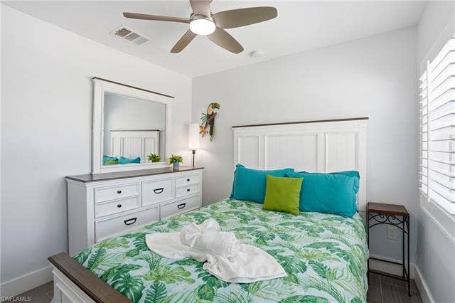 240 Fairweather Ln, Fort Myers Beach, FL 33931 Bedroom featuring a white paneled headboard and a coordinating dresser with dark hardware - Virtually Edited Image
