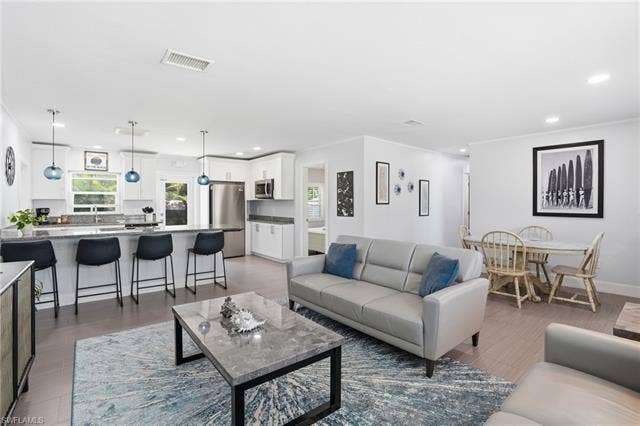 240 Fairweather Ln, Fort Myers Beach, FL 33931 Open-concept living space featuring wood-finish flooring, recessed lighting, and a white color palette - Virtually Edited Image