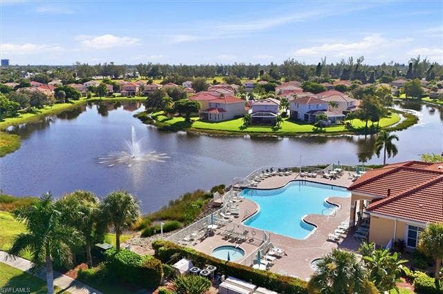 8910 Paseo De Valencia St, Fort Myers, FL 33908 Clubhouse, infinity edge resort pool, hot tub, and kiddie pool overlooking lake with fountain.