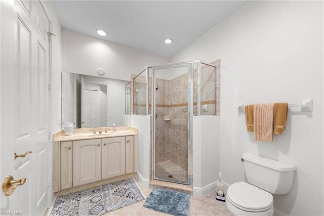 3142 Aviamar Cir, #2104, Naples, FL 34114 Bathroom featuring a built-in vanity with a light-toned countertop, a frameless mirror, a glass-enclosed shower with tiled walls, and a white toilet