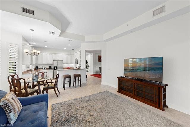 3142 Aviamar Cir, #2104, Naples, FL 34114 Kitchen featuring white cabinetry, stainless steel refrigerator, and a breakfast bar with stone countertops