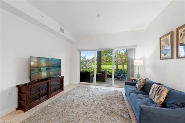 3142 Aviamar Cir, #2104, Naples, FL 34114 Glass sliding doors open to an outdoor patio with a water feature