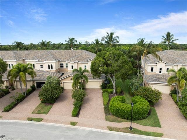 3142 Aviamar Cir, #2104, Naples, FL 34114 Townhome residences with barrel tile roofs, attached garages, and mature tropical landscaping