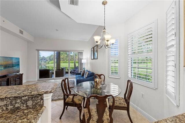 3142 Aviamar Cir, #2104, Naples, FL 34114 Open-concept living area with large sliding glass doors, a decorative ceiling fixture, and white plantation shutters
