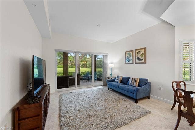 3142 Aviamar Cir, #2104, Naples, FL 34114 Sliding glass doors leading to an outdoor living space, vaulted ceiling, neutral wall tones, plantation shutters, and large format tile flooring