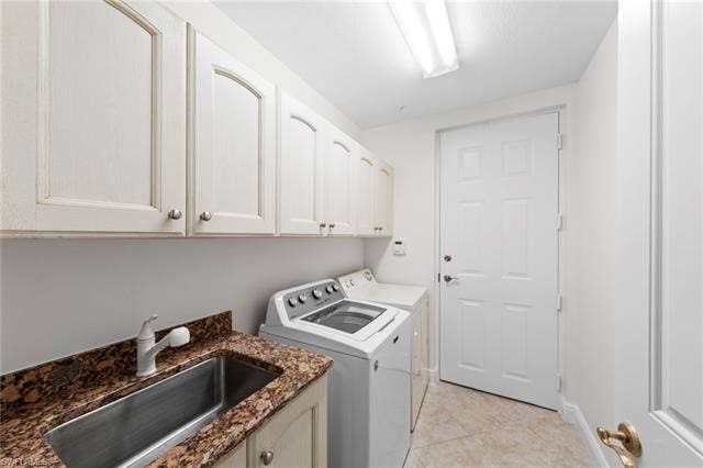 3142 Aviamar Cir, #2104, Naples, FL 34114 Utility room featuring upper cabinetry, a stainless steel sink, a stone countertop, and tile flooring