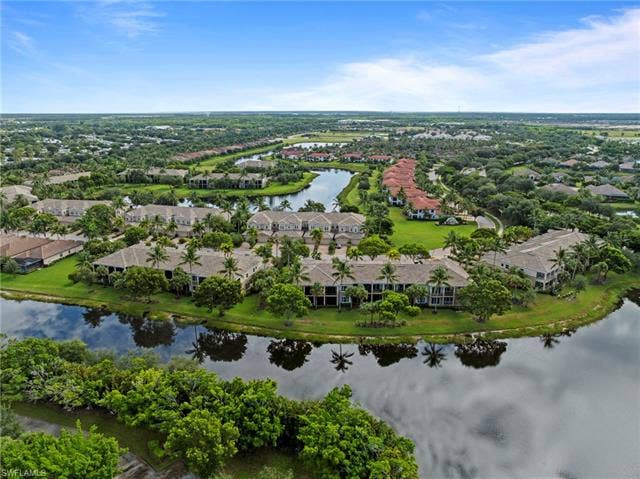 3142 Aviamar Cir, #2104, Naples, FL 34114 Lakeside community with multiple structures featuring tile roofs and private balconies, surrounded by mature trees and manicured lawns