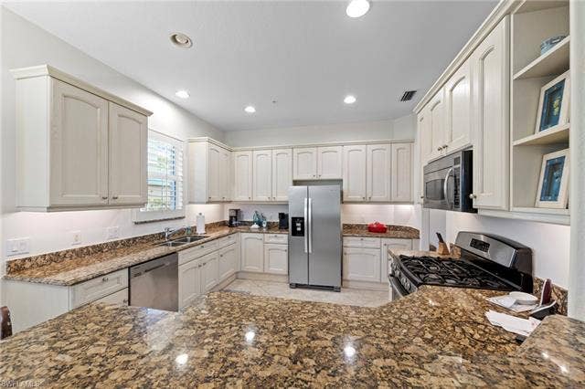 3142 Aviamar Cir, #2104, Naples, FL 34114 U-shaped kitchen featuring stone countertops, abundant cabinetry, stainless steel appliances, and recessed lighting