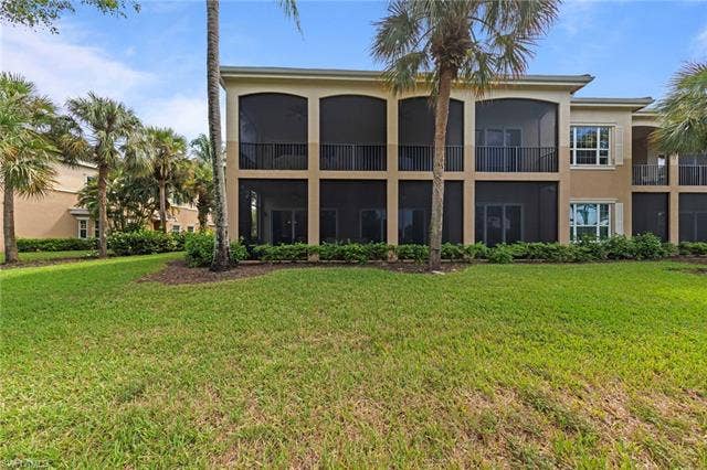 3142 Aviamar Cir, #2104, Naples, FL 34114 Two-story building exterior featuring screened-in balconies and patios, mature palm trees, and a manicured lawn