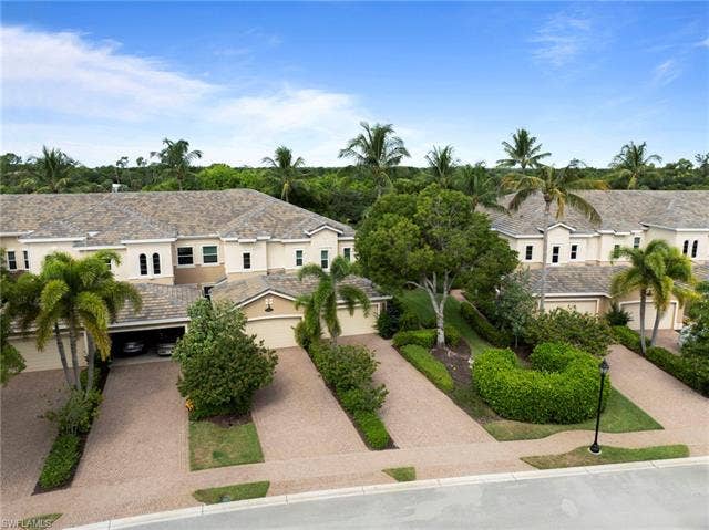 3142 Aviamar Cir, #2104, Naples, FL 34114 Stucco exterior with multiple rooflines, attached garages, paved driveways, and mature landscaping