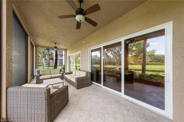 3142 Aviamar Cir, #2104, Naples, FL 34114 Screened patio with tiled flooring, two ceiling fans, and multiple sliding glass doors
