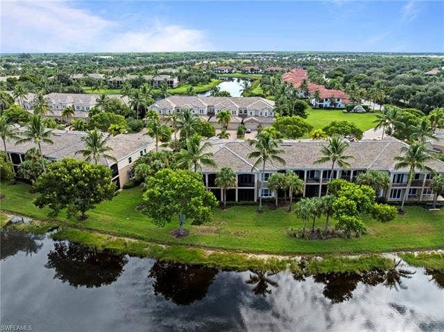 3142 Aviamar Cir, #2104, Naples, FL 34114 Waterfront community with lush landscaping, mature palm trees, and multiple residential structures